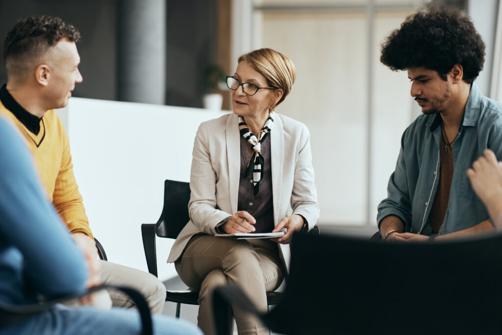 Mental health professional counseling group therapy members at communicating center.