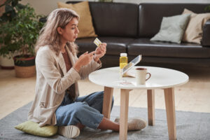 Horizontal shot of modern young adult woman sitting in front of digital tablet at home talking to doctor about meds on video call