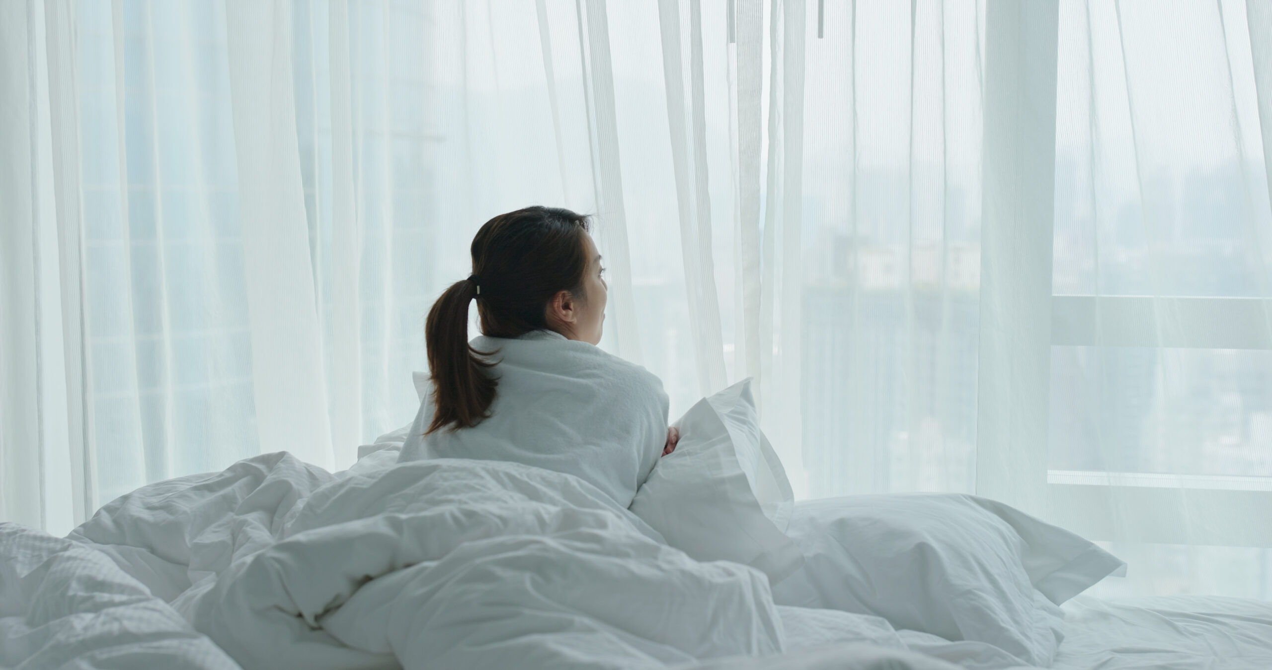 woman laying on a bed looking out the window