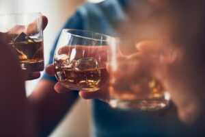 A closeup shot of many people clinking glasses with alcohol at a toast