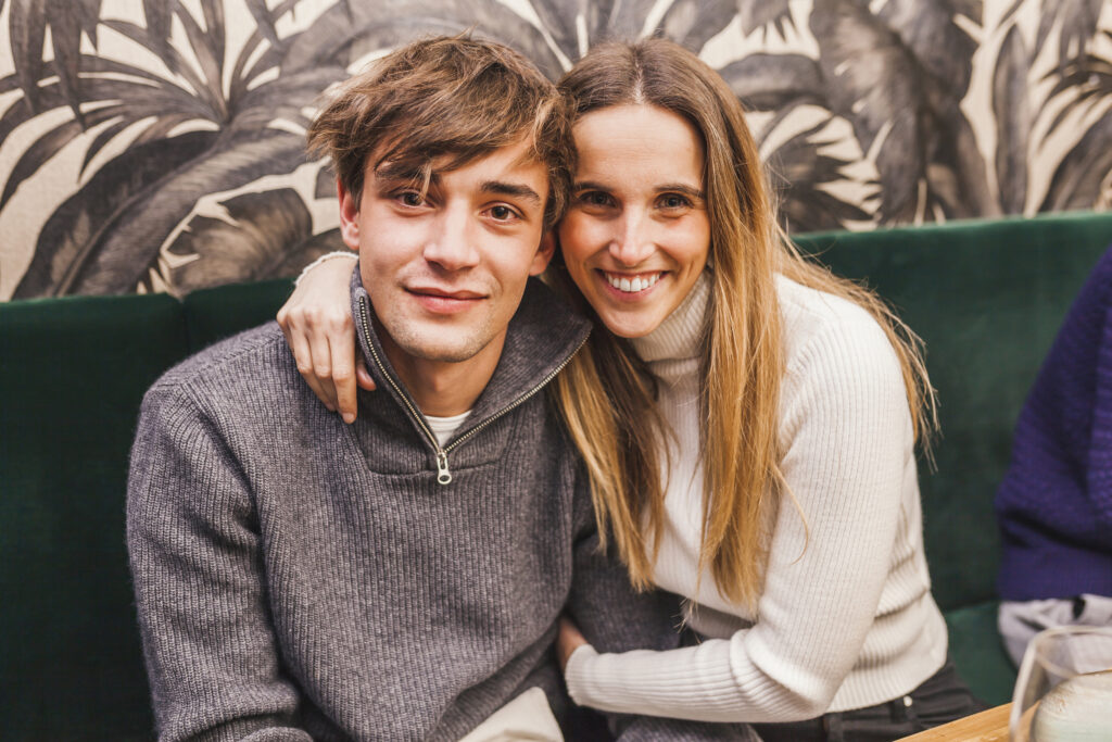 Cheerful sister hugging her brother while looking at camera at a dinner party