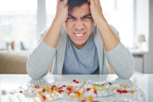 Angry man sitting at the table with pills on it