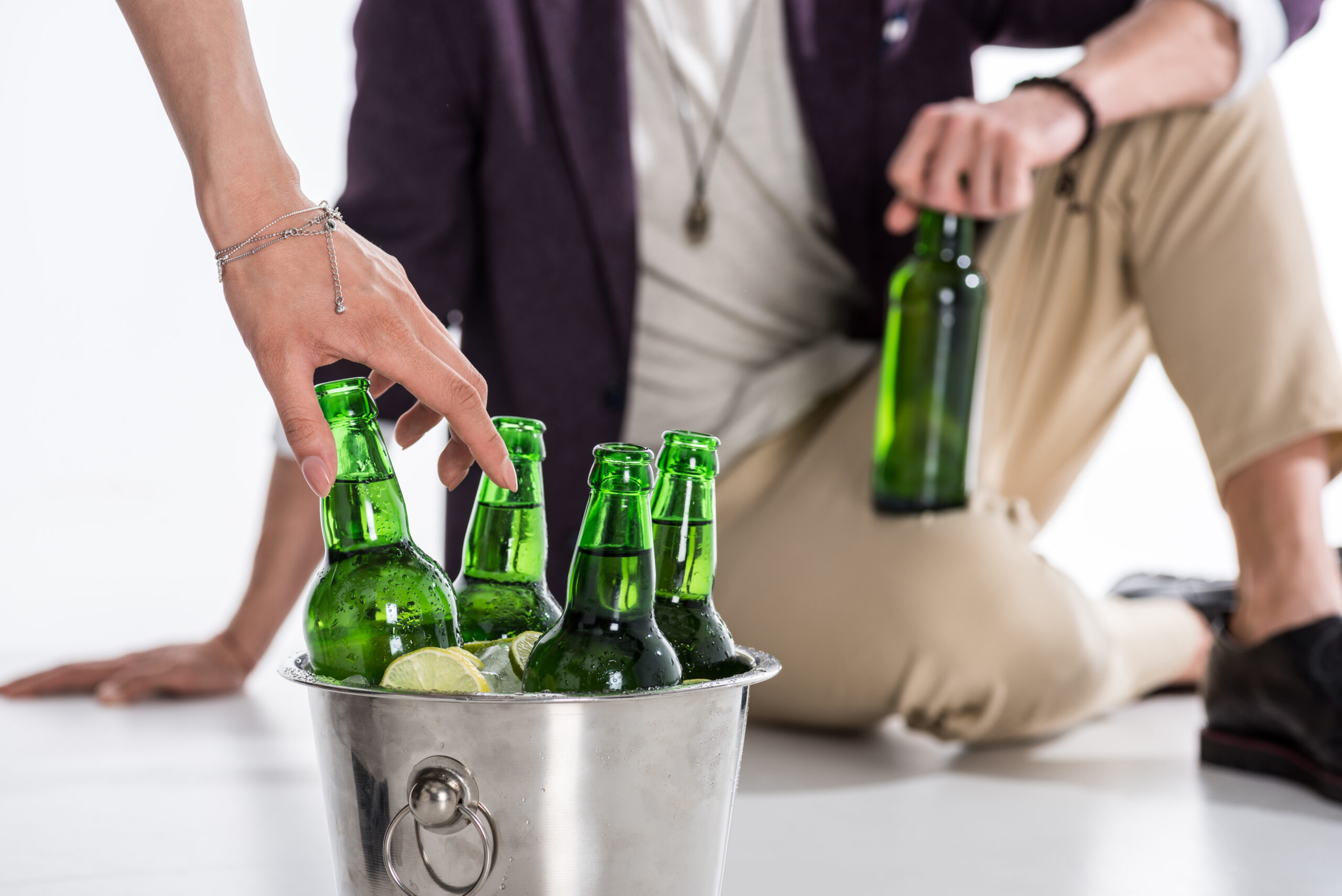 Cropped shot of people holding glass bottles and bucket full of ice and beer bottles