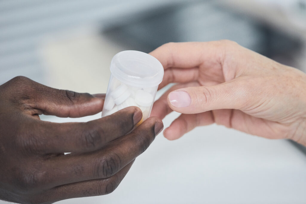 Close-up of African man giving bottle with medicine to woman