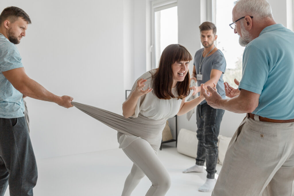 Young woman screaming releasing her anger on group therapy