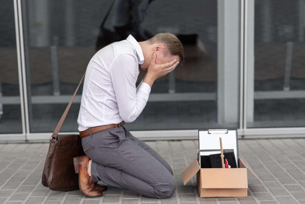 man who is going through withdrawal at work has fallen to his knees with his head in his hands