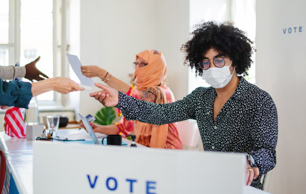 Group of people with face masks voting in polling place, usa elections and coronavirus.