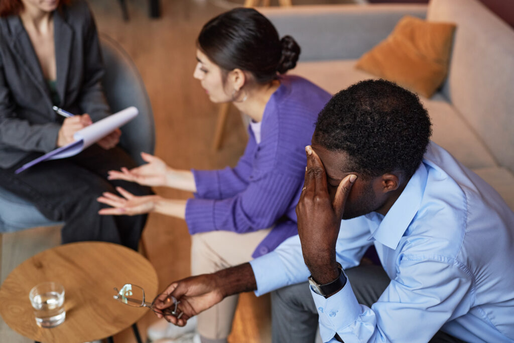 Stressed man visiting family psychologist with his wife