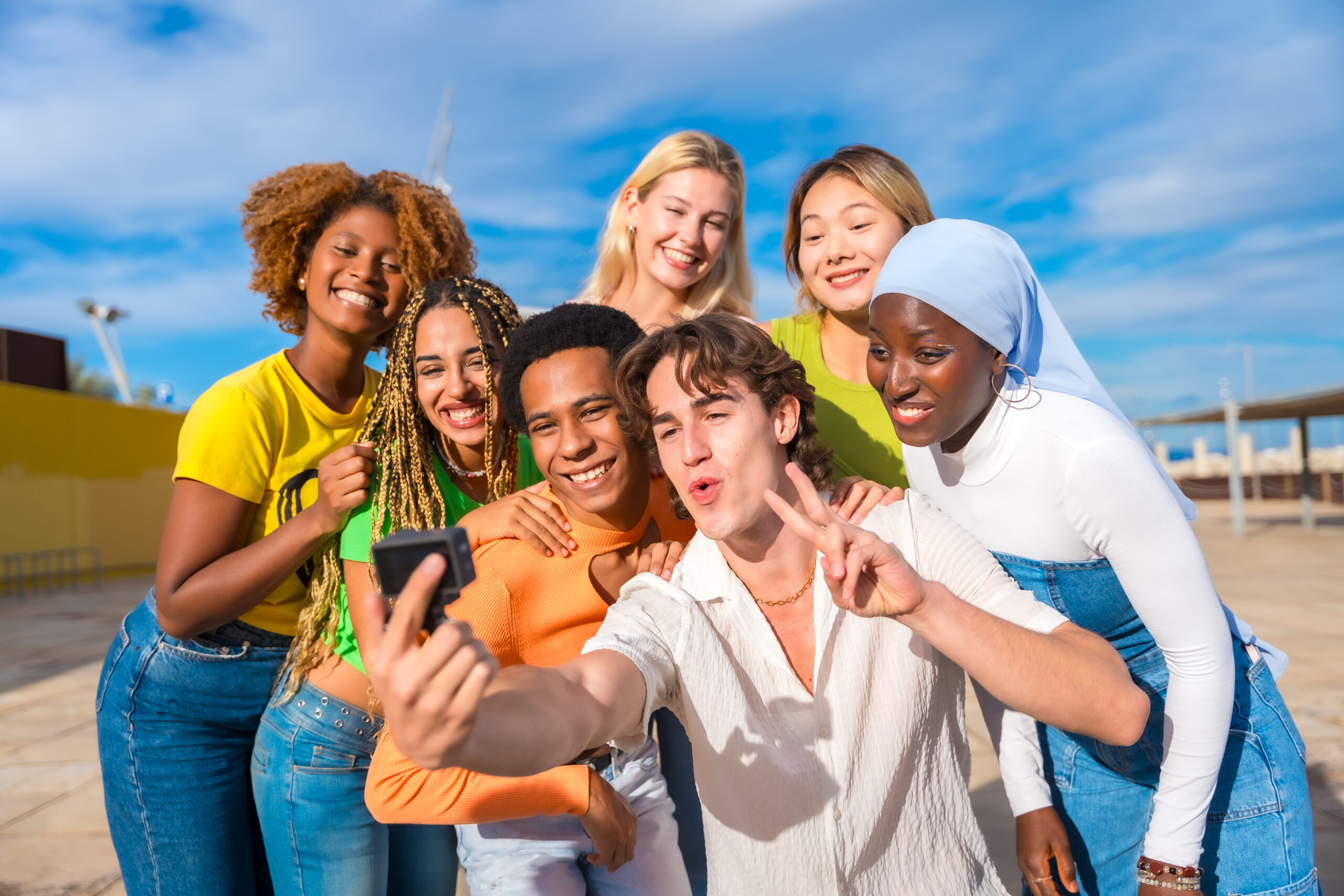 Multi-ethnic and gender friends gesturing success while taking a selfie