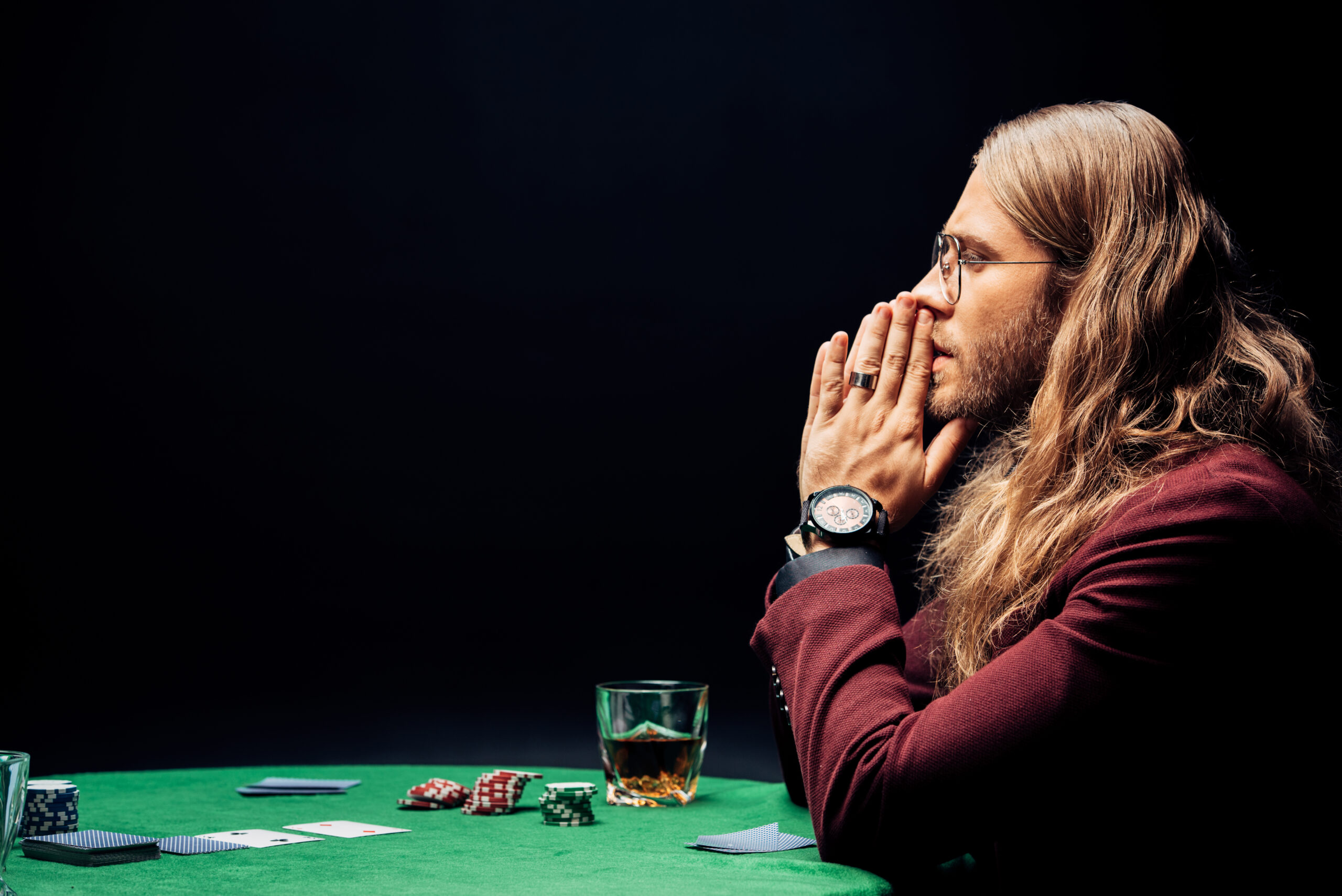 man struggling with gambling addiction sitting at a poker table