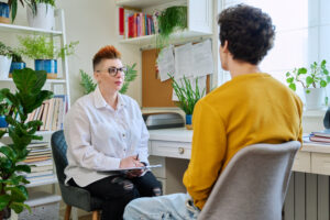 Female professional psychologist mental therapist working with young guy in office. Social worker counselor psychotherapist helping patient with difficulties stress depression. Psychology psychotherapy