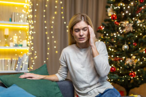 woman sitting on the couch in her living room stressed about the holidays