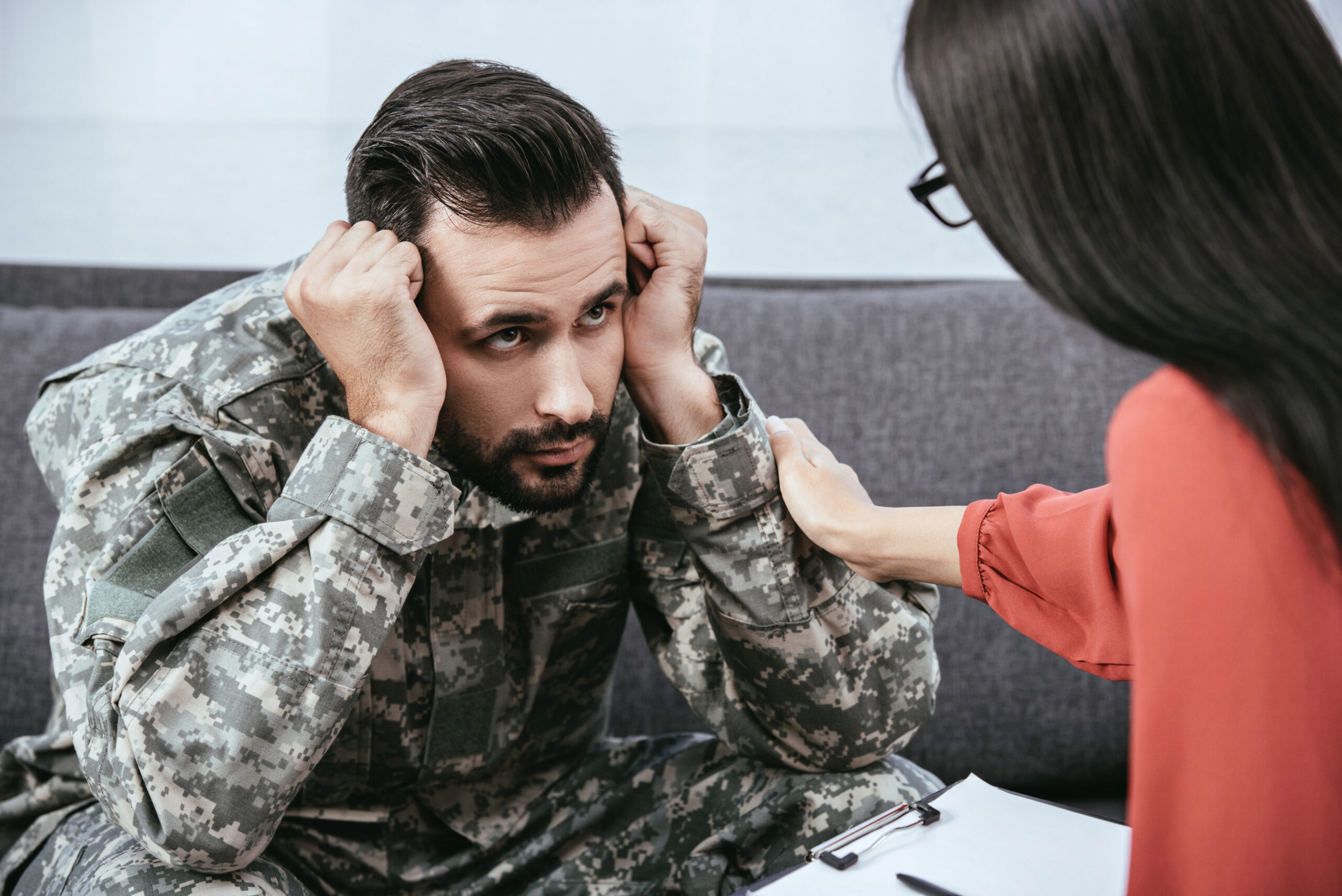 depressed soldier with post traumatic syndrome looking at psychiatrist during session