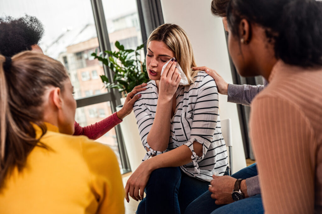 Diverse group of people sitting in circle in group therapy session.