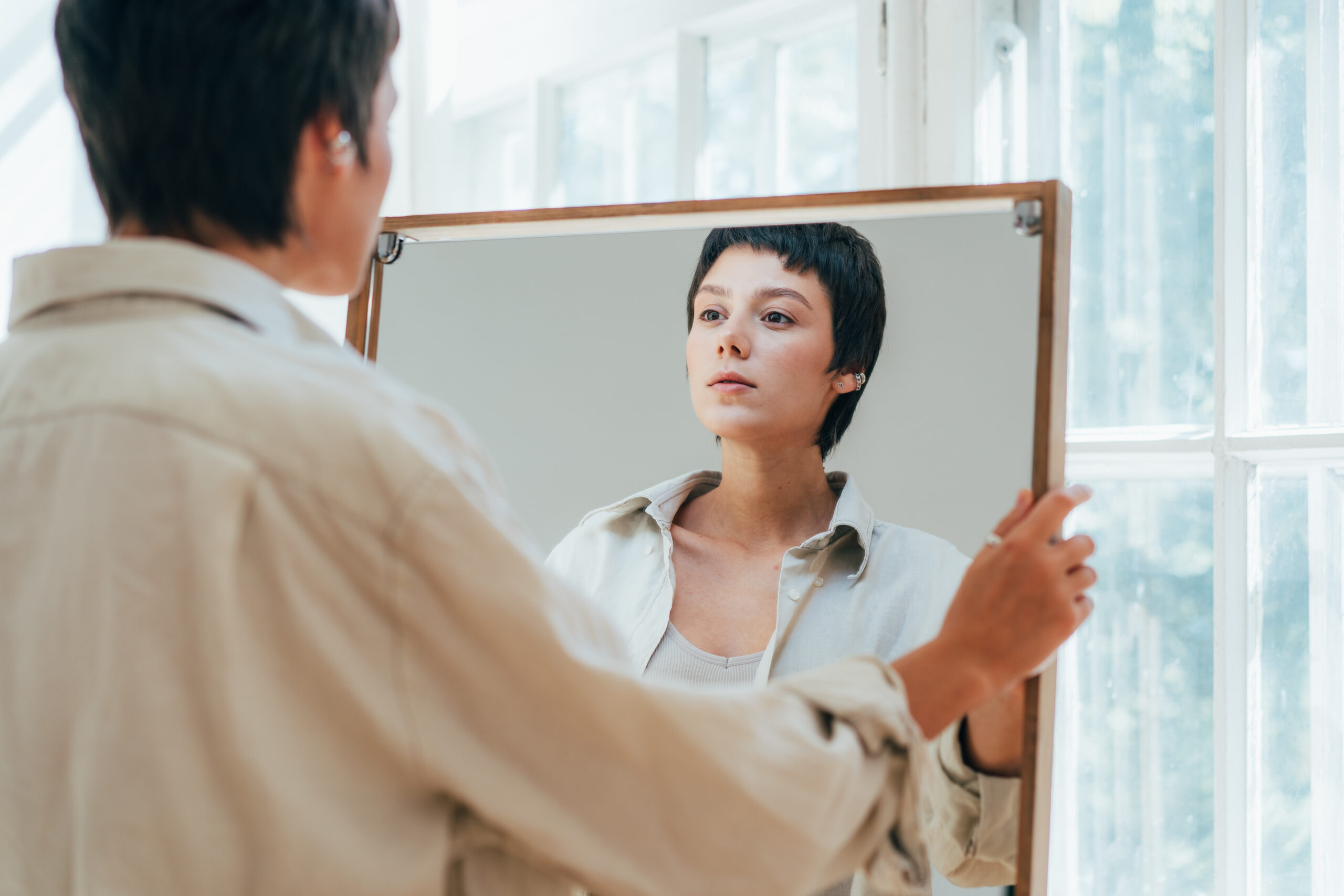 A young attractive woman peers at her reflection in the mirror.