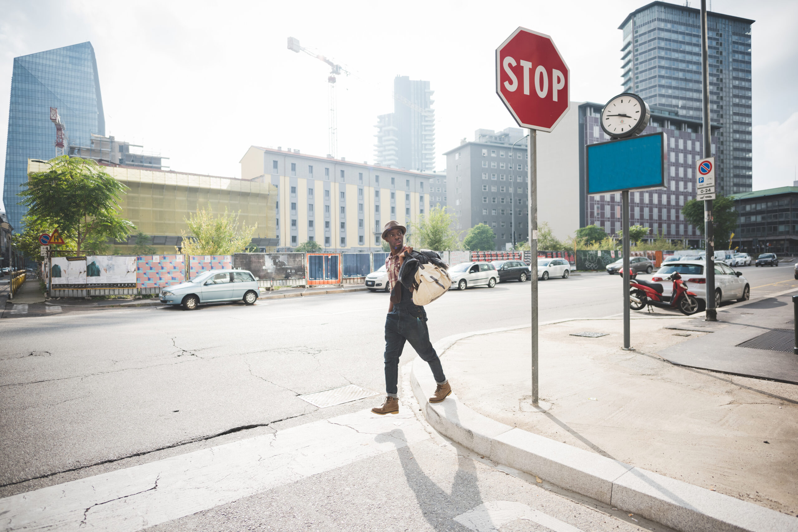 Young handsome afro man walking outdoor in the city holding a bag crossing street - traveler, strolling concept