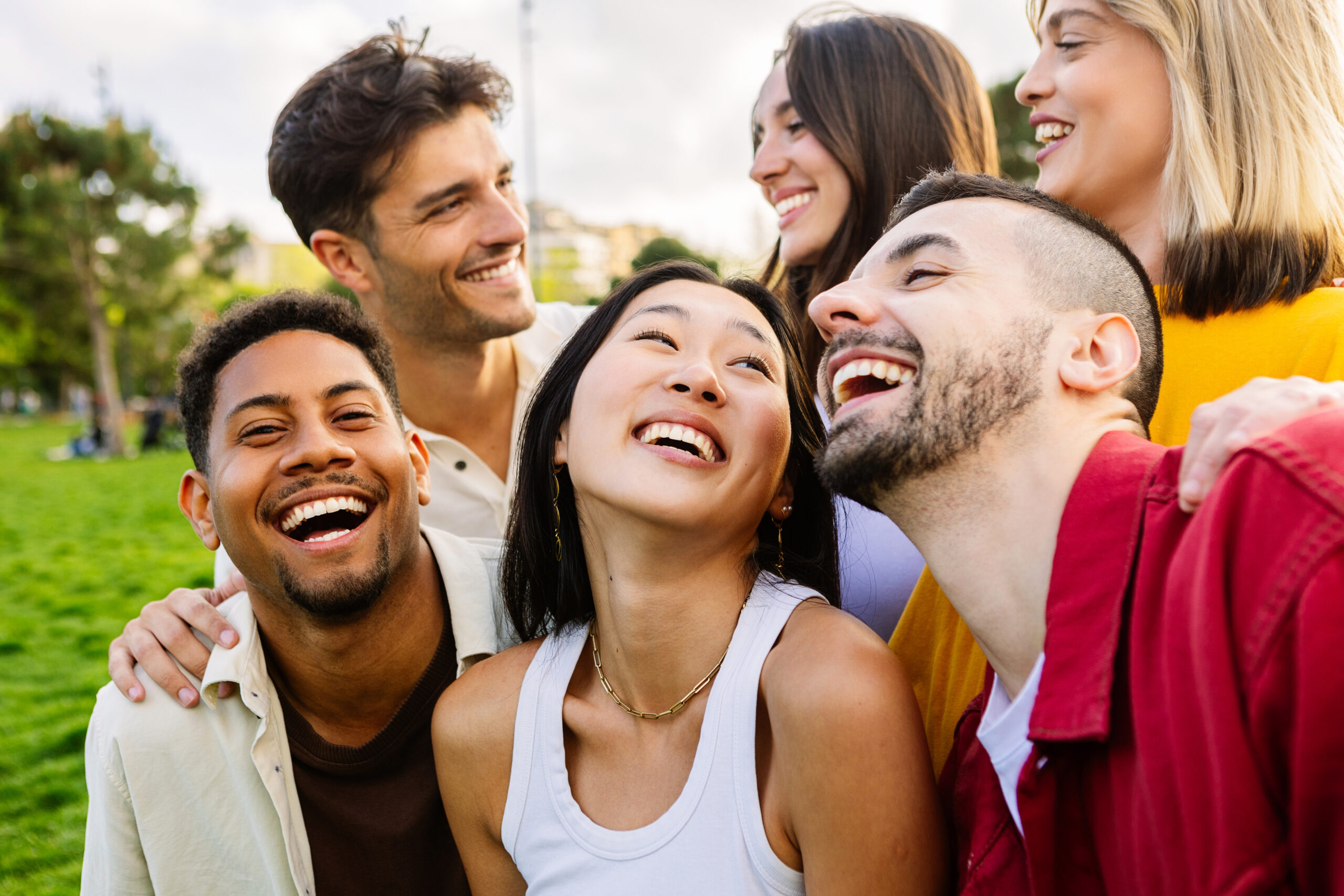 Diverse group of young friends having fun together outdoors in summer. Millennial student people laughing walking in city street enjoying holiday. Youth community and friendship concept.