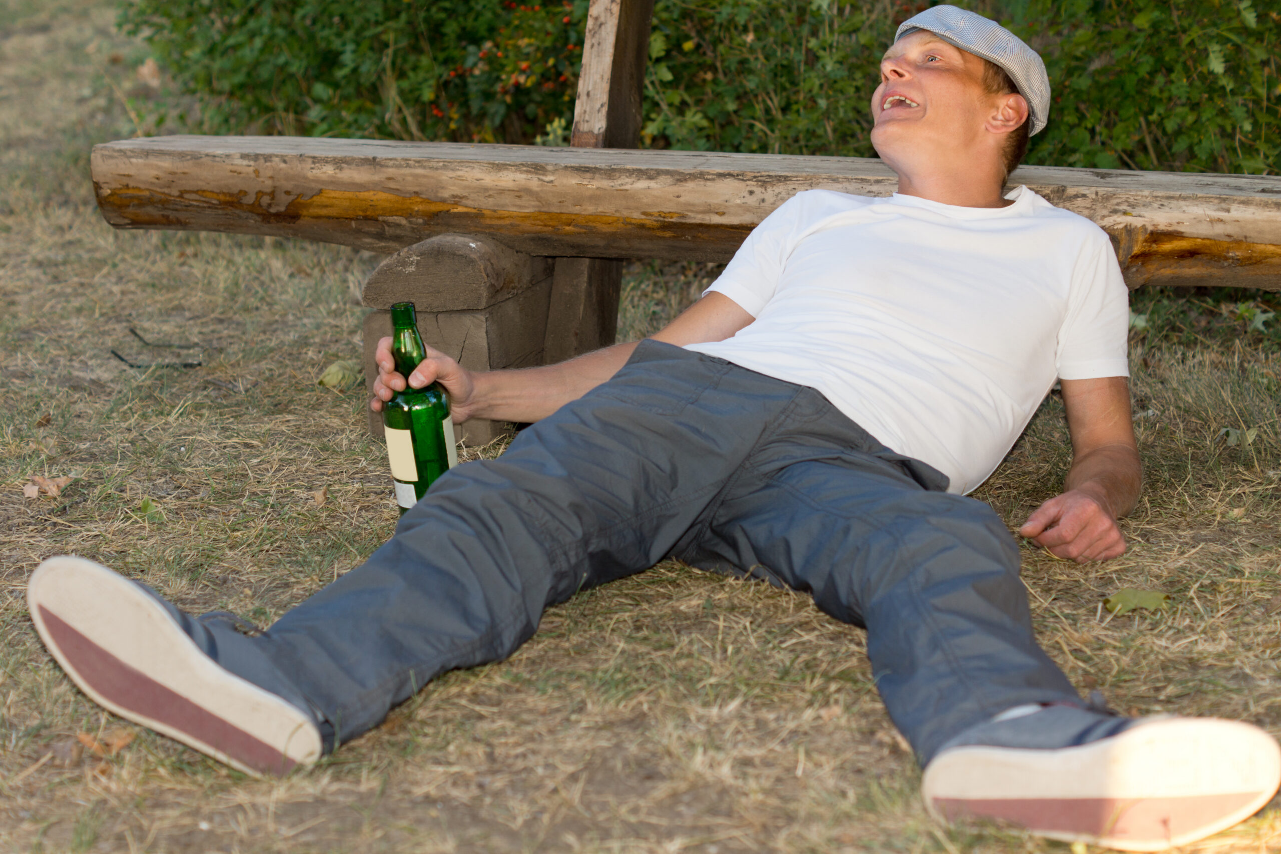man-lying-on-ground-with-beer-bottle