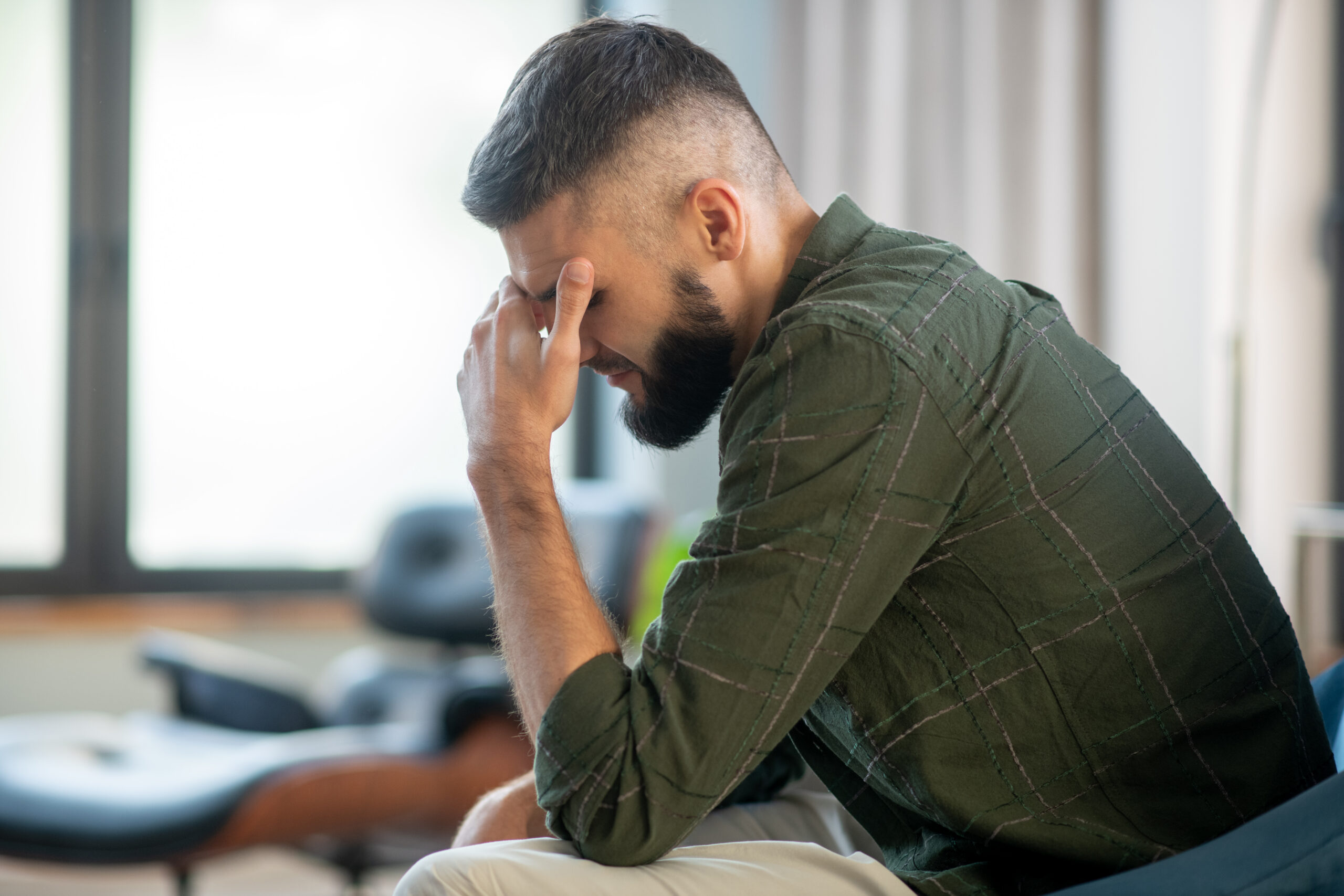 Man near window. Bearded mature man sitting near window and waiting for his psychoanalyst
